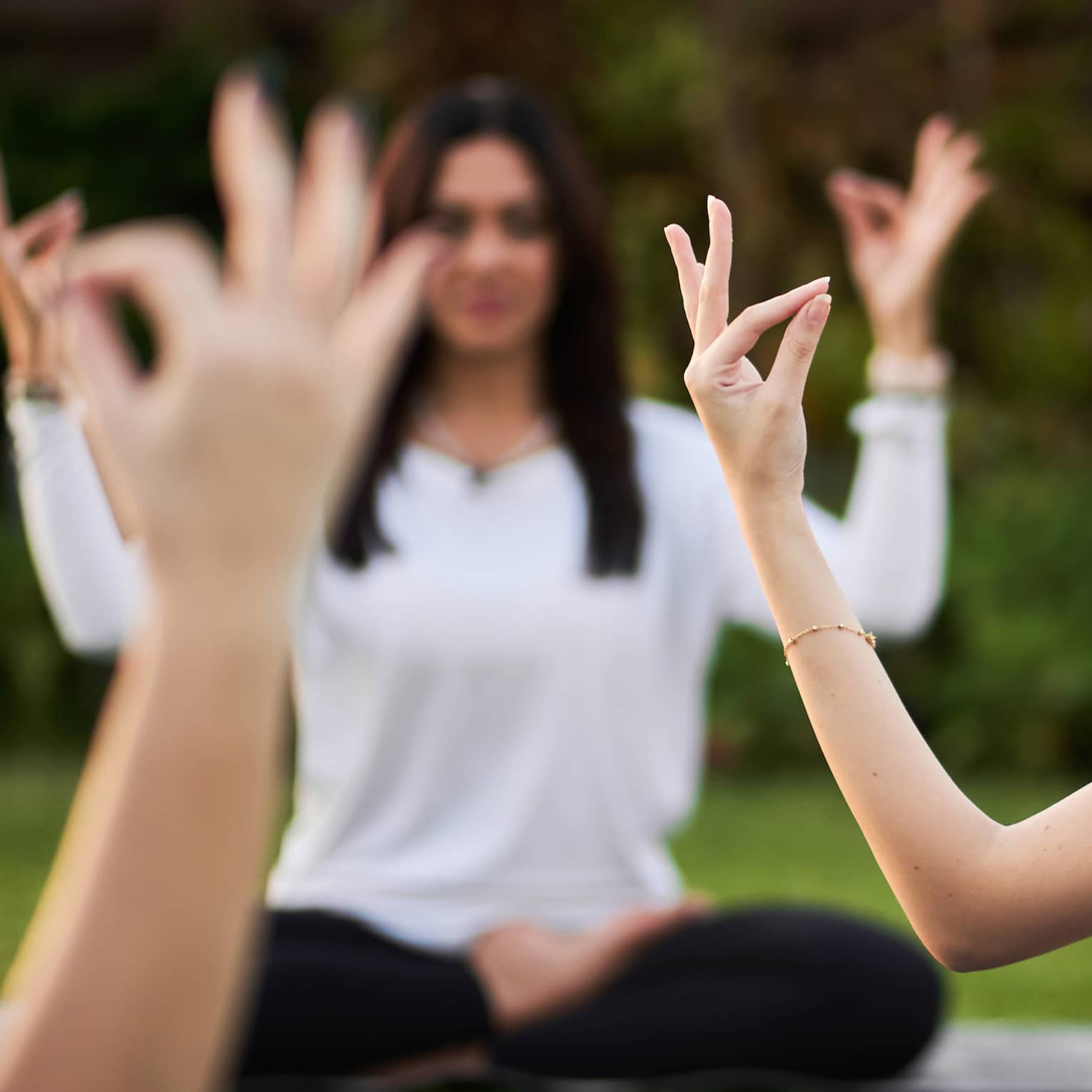 Guests doing yoga outdoors on yoga mats with trees in the background