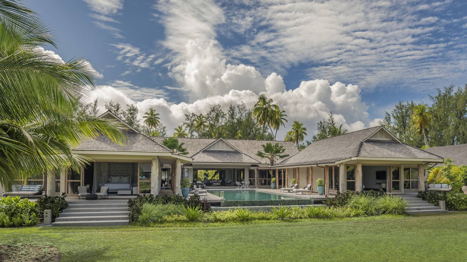 Residence villa with three buildings surrounding private pool, surrounded by palm trees