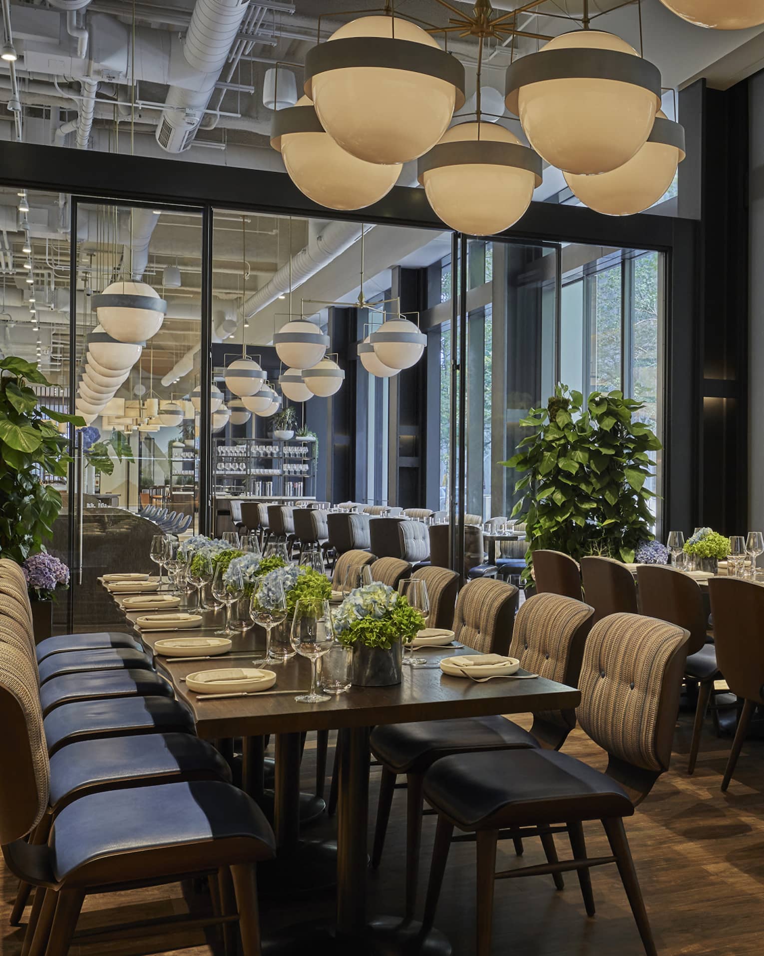 Two long tables are set with plates and white floral arrangements in Vernick Restaurant in Four Seasons Philadelphia 