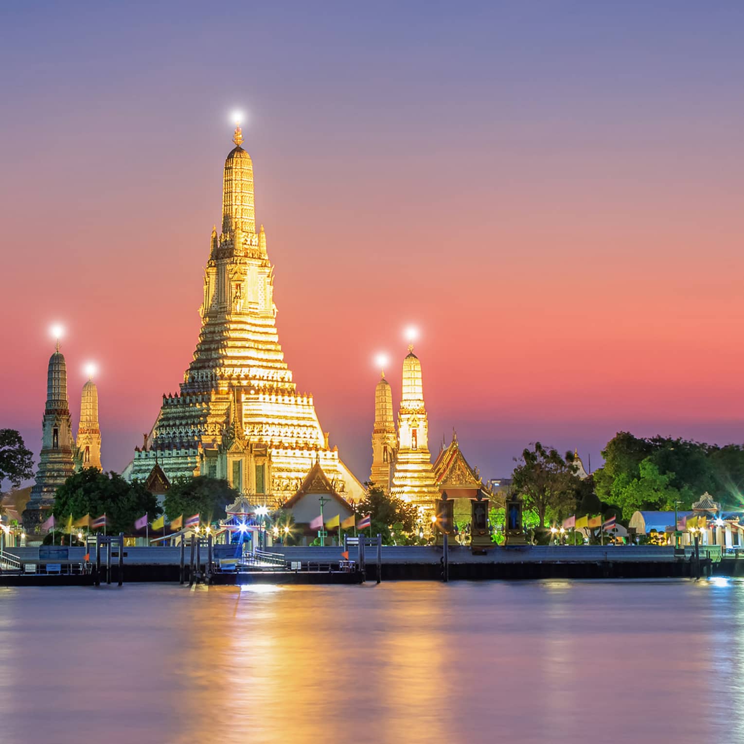 A large structure covered in lights on the shore of water.