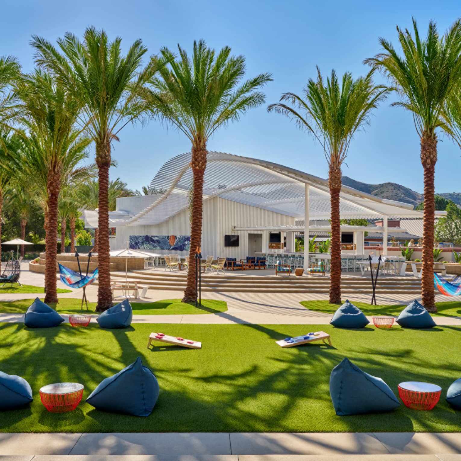 An outdoor sitting area with beanbag chairs and palm trees.