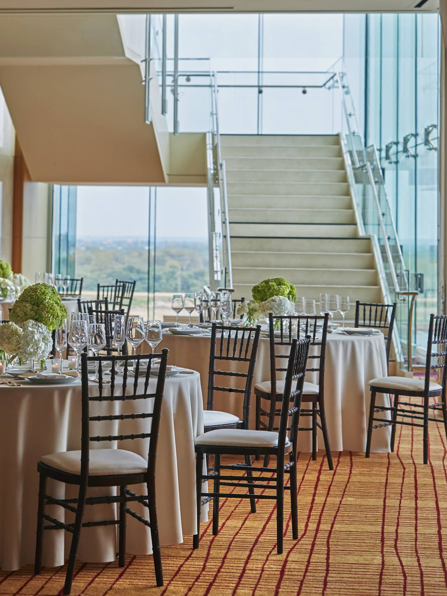 Ballroom, round banquet tables at bottom of large white staircase 