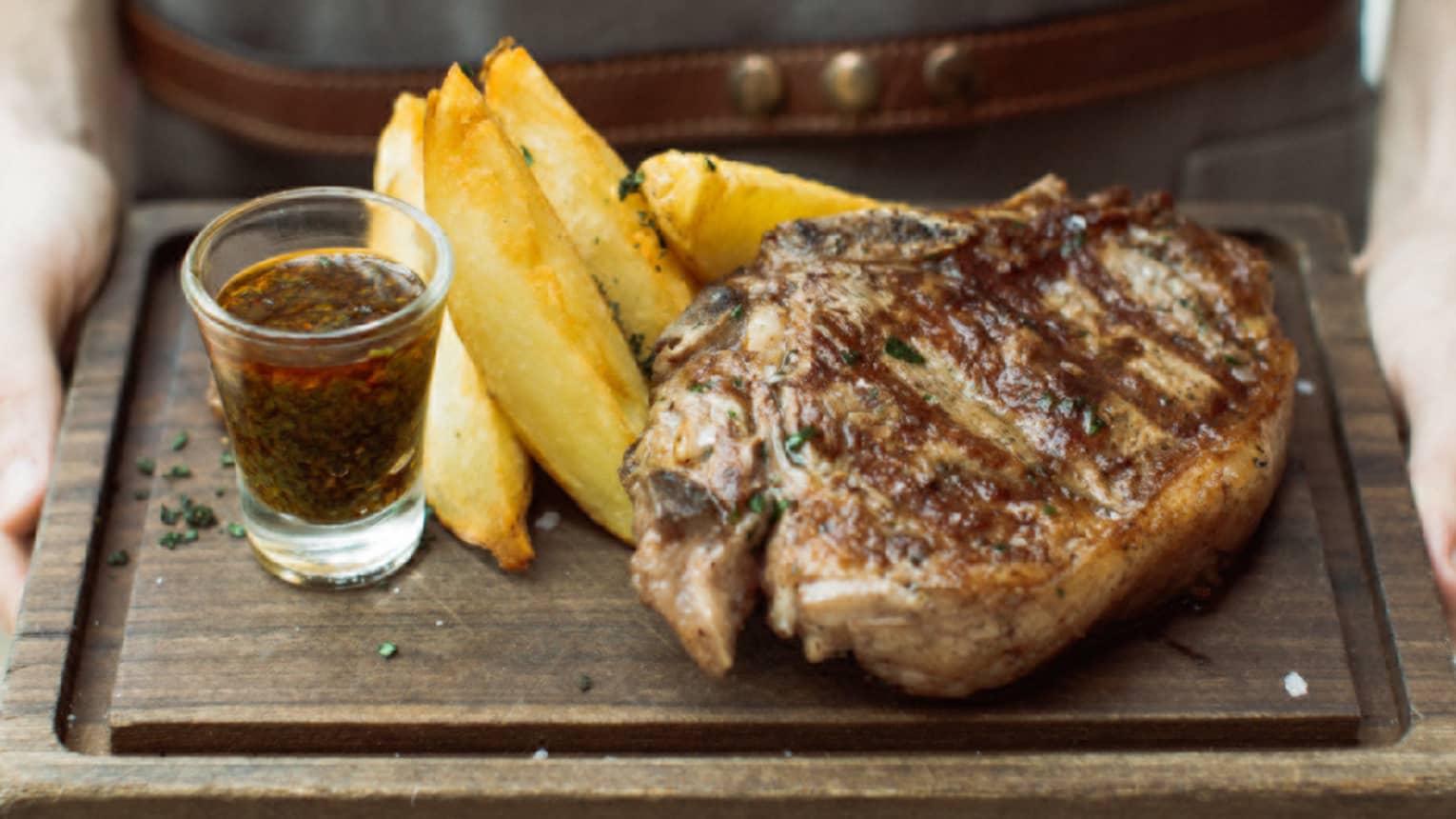 a 400-gram rib eye is served with chimichurri sauce and potato wedges
