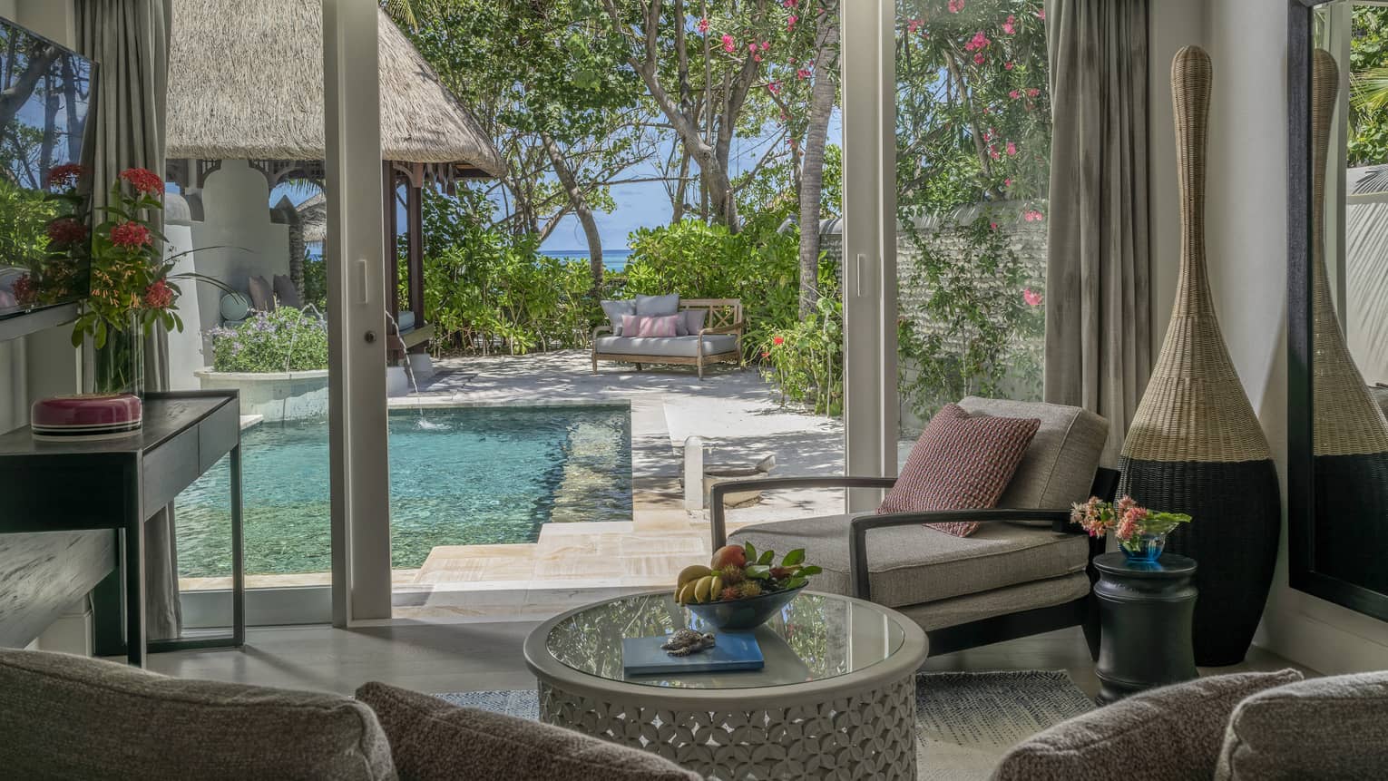 Living room opening to pool deck, with beach in the distance