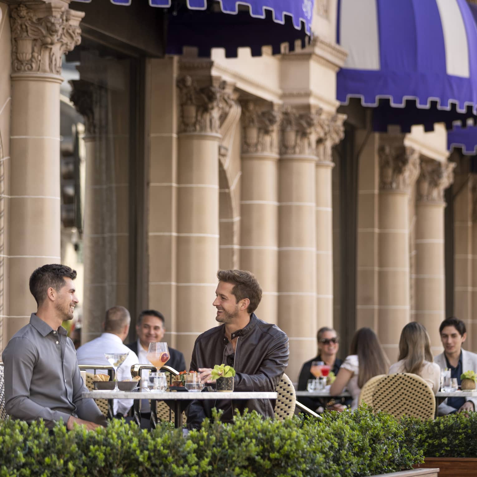 Small groups of people sitting and dining on an outside patio.