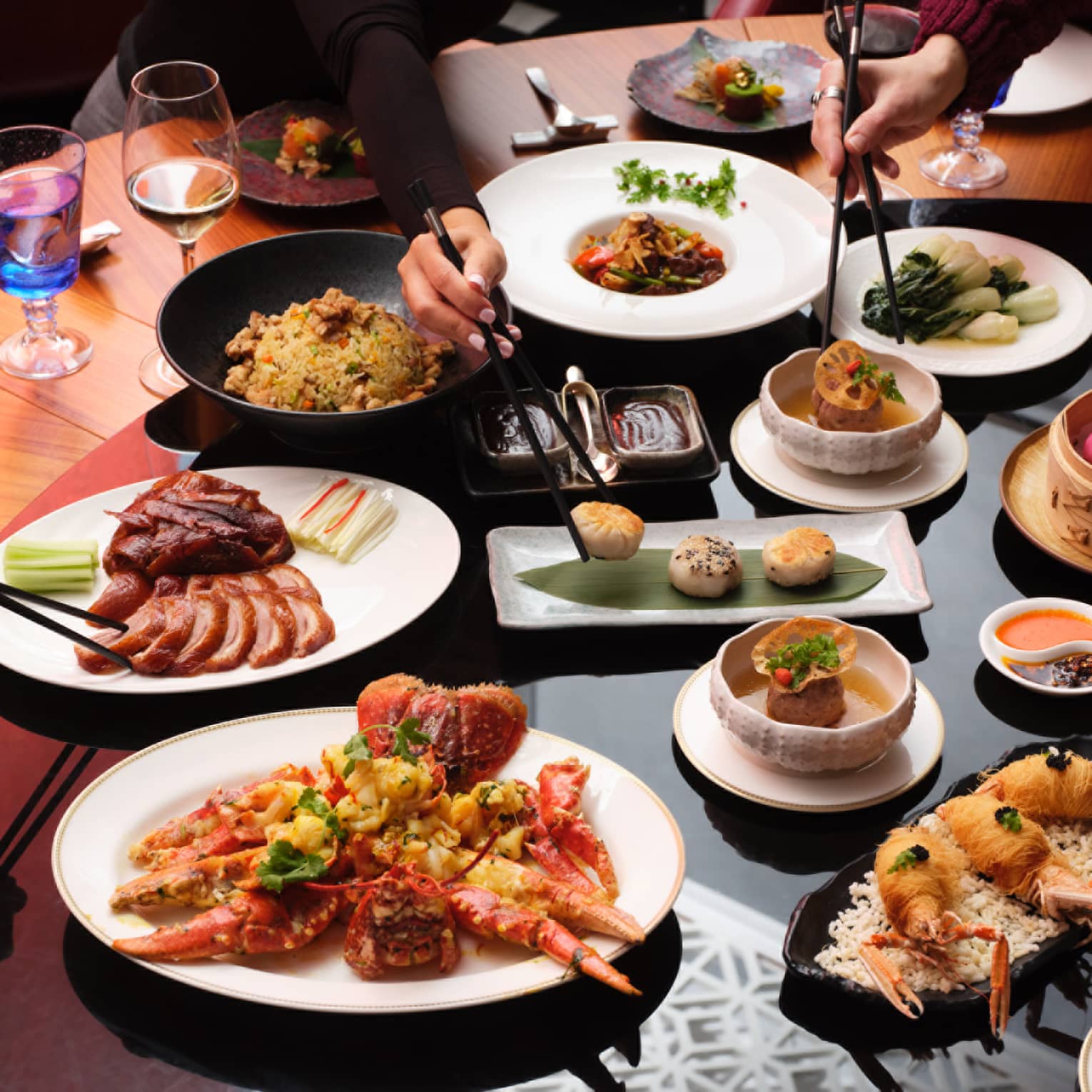 Round dining table with various dishes that people share, including meat and fried shellfish