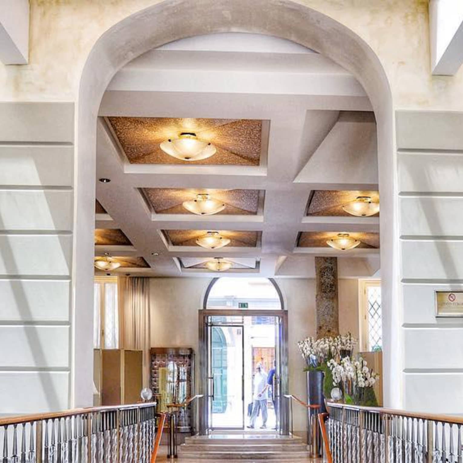 Four Seasons Hotel Milan lobby with tall stone archways, flowers, lights
