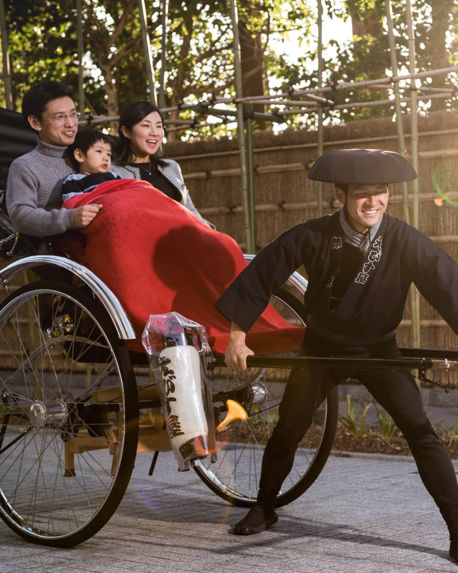 Couple, young boy under red blanket ride in rickshaw wagon pulled by man