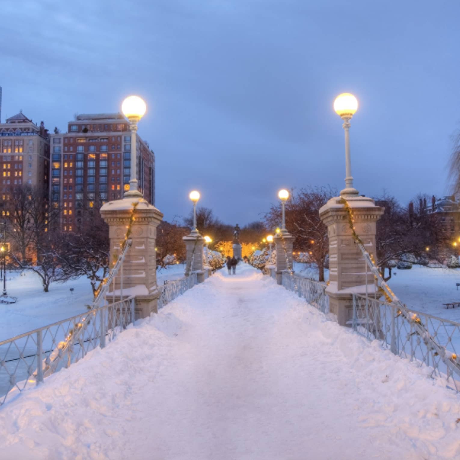 Bridge at night time covered in snow with city buildings in the background