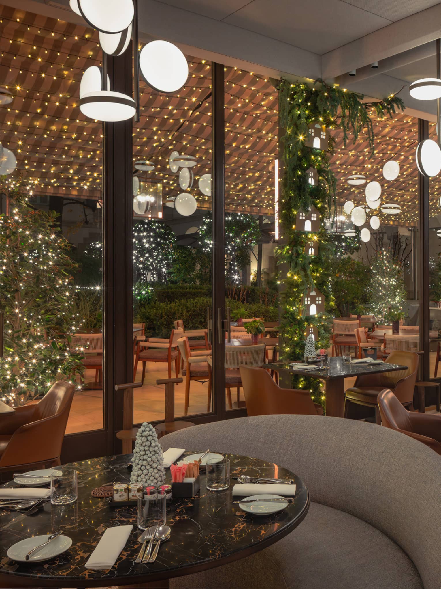 A chic interior dining space decorated with festive greenery and lights