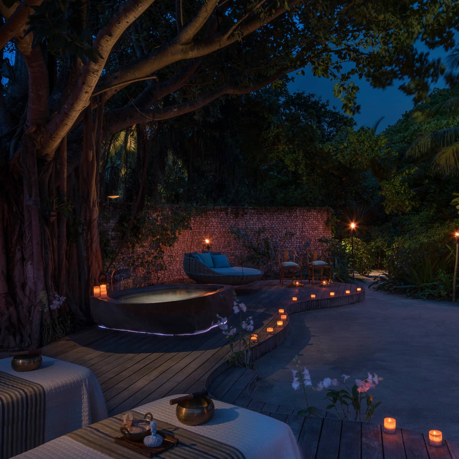 Candles along sand beach, spa patio, hot tub at night