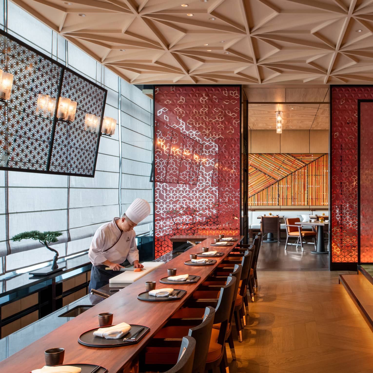 Chef prepares food at long dining bar at Yotsuba Japanese restaurant