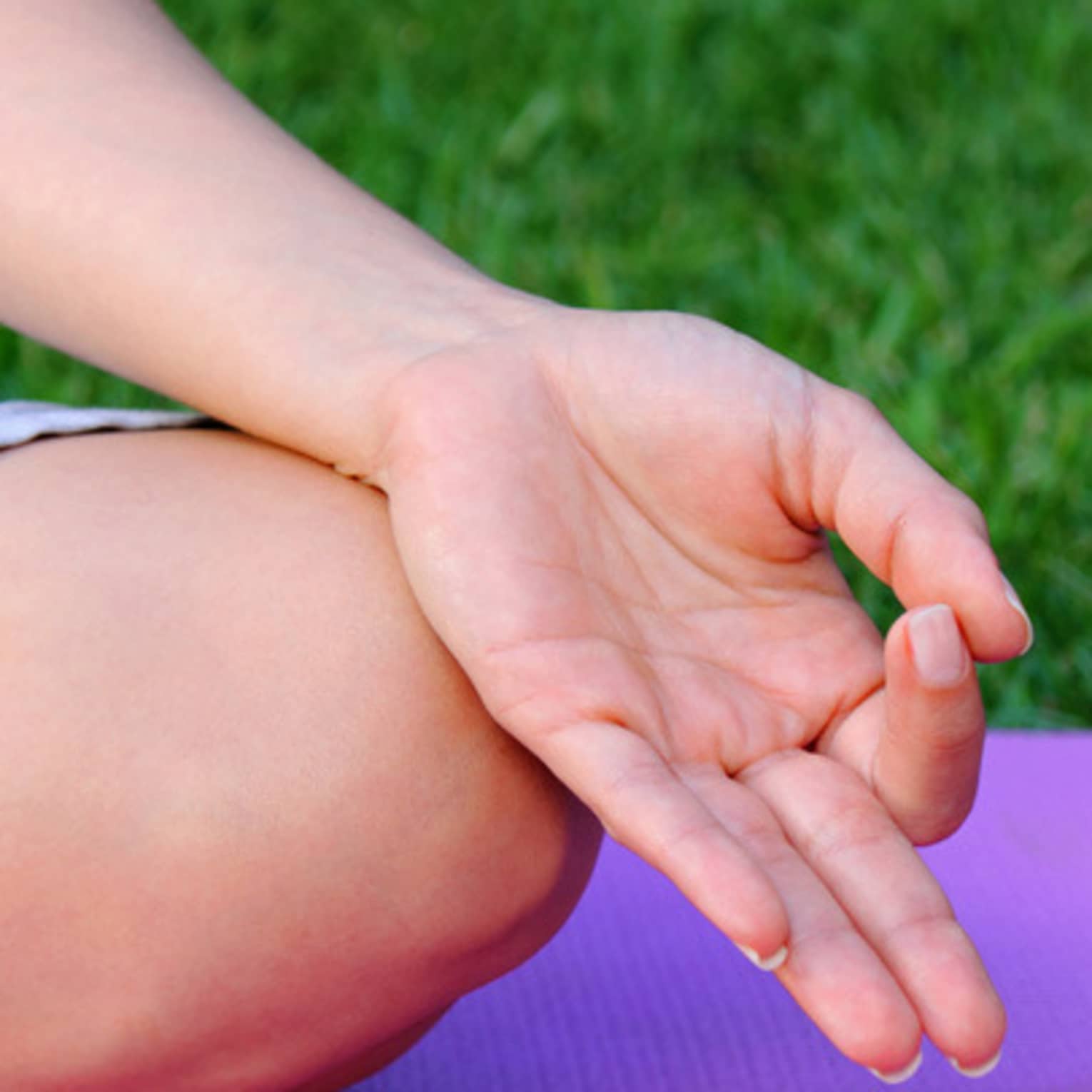 Side of hand, leg in cross legged meditation pose on yoga mat 