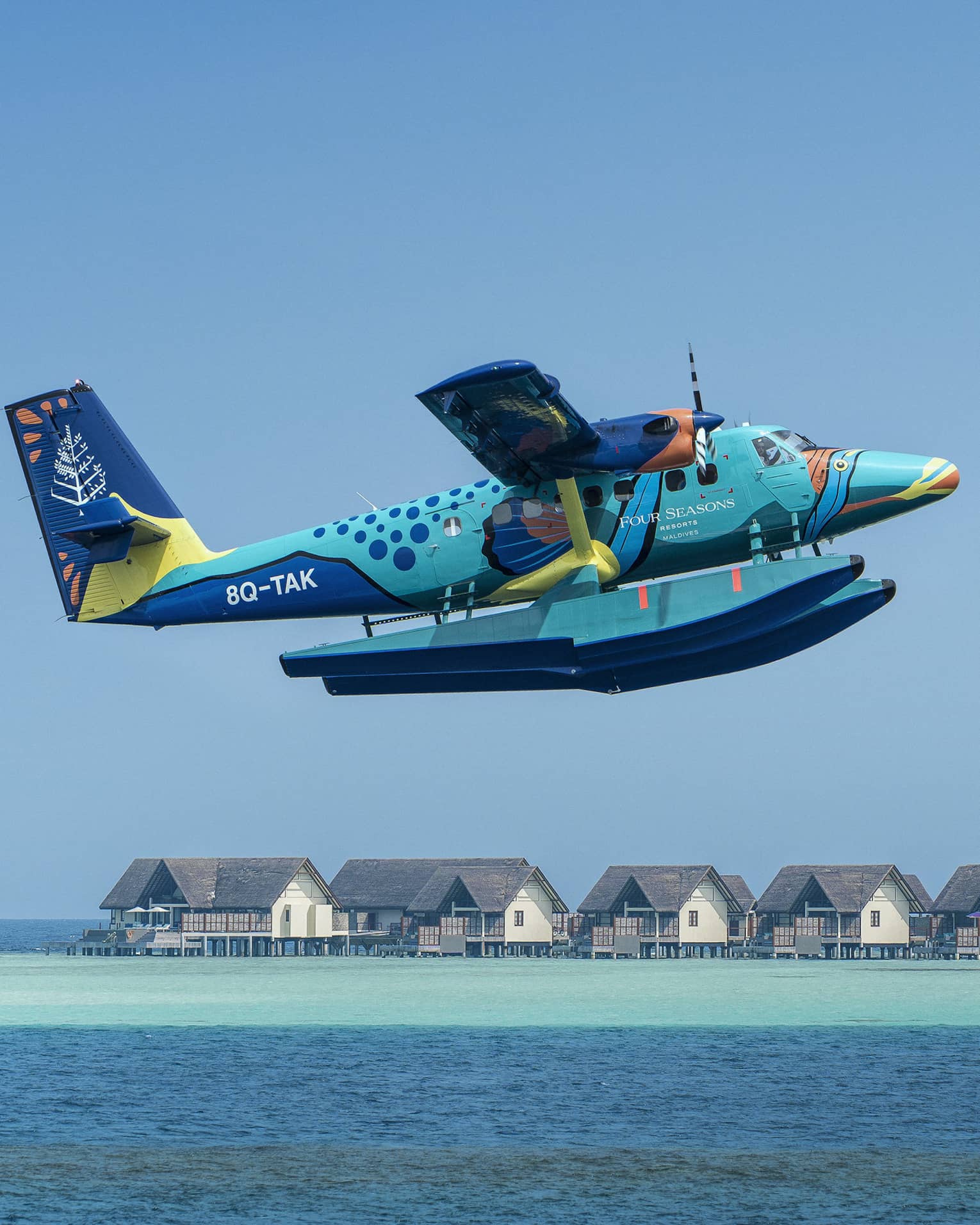 Maldives Sea Plane taking off with water villas and palm trees in the background