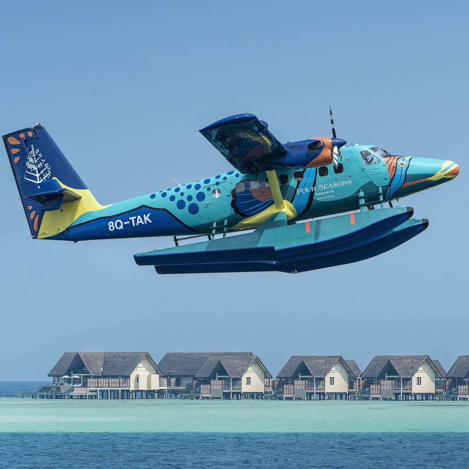 Maldives Sea Plane taking off with water villas and palm trees in the background
