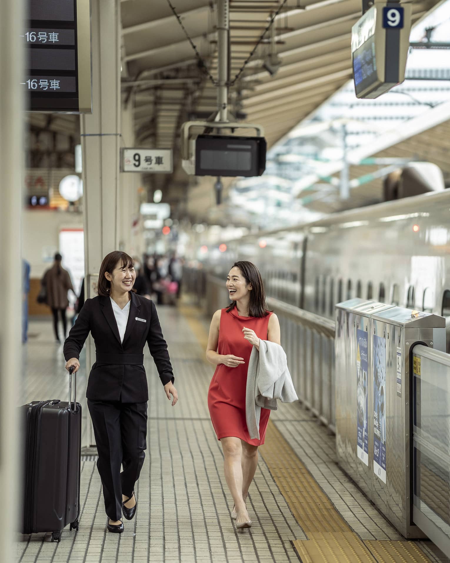 Train station greeter walks with female guest along the train platform