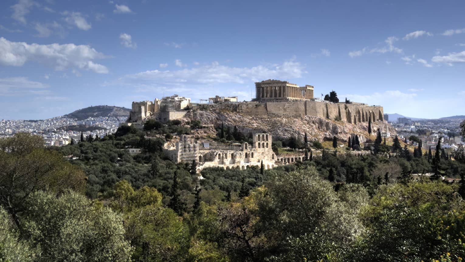 Ancient ruins of Acropolis on mountain surrounded by greenery 