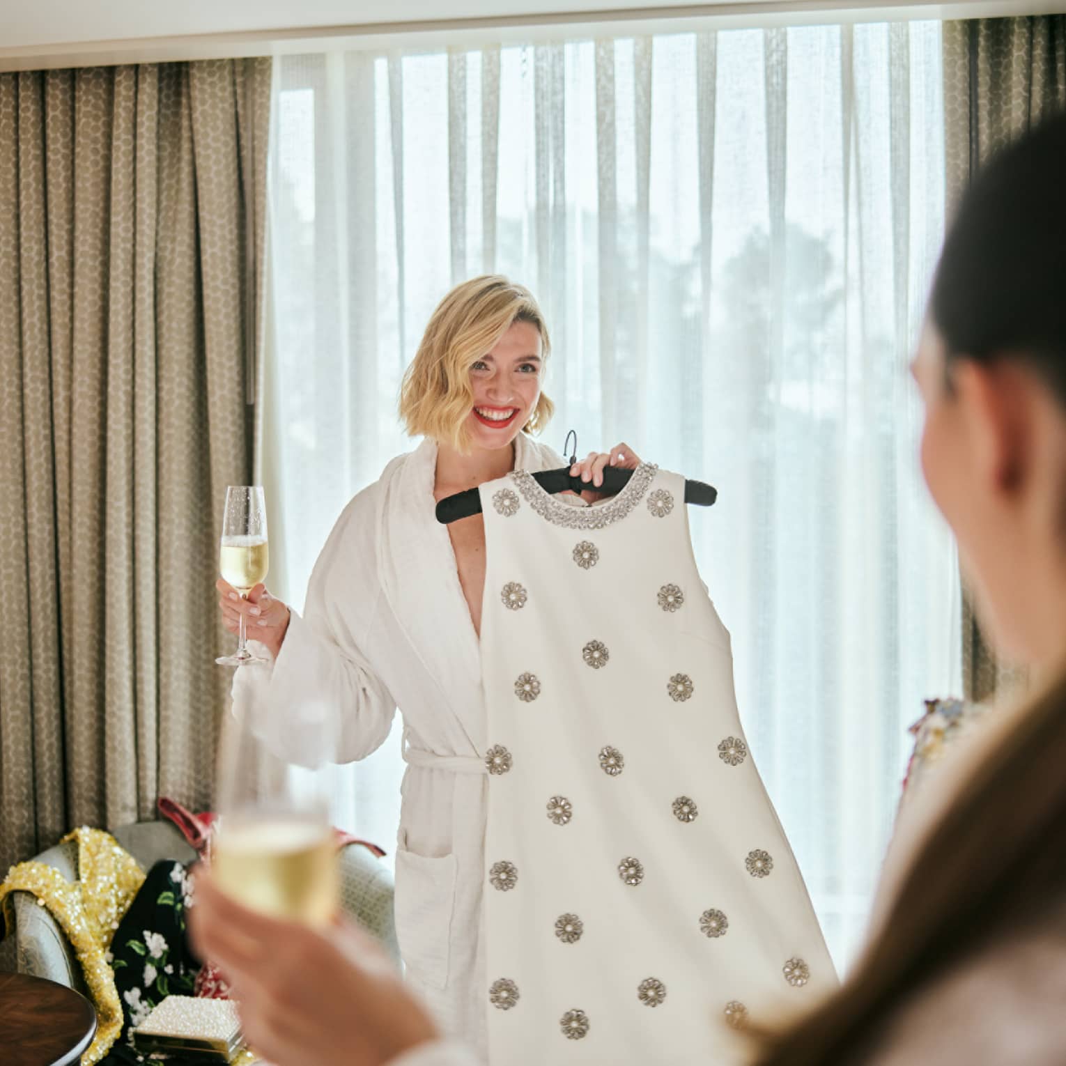 A person wearing a robe and holding a dress on a hanger