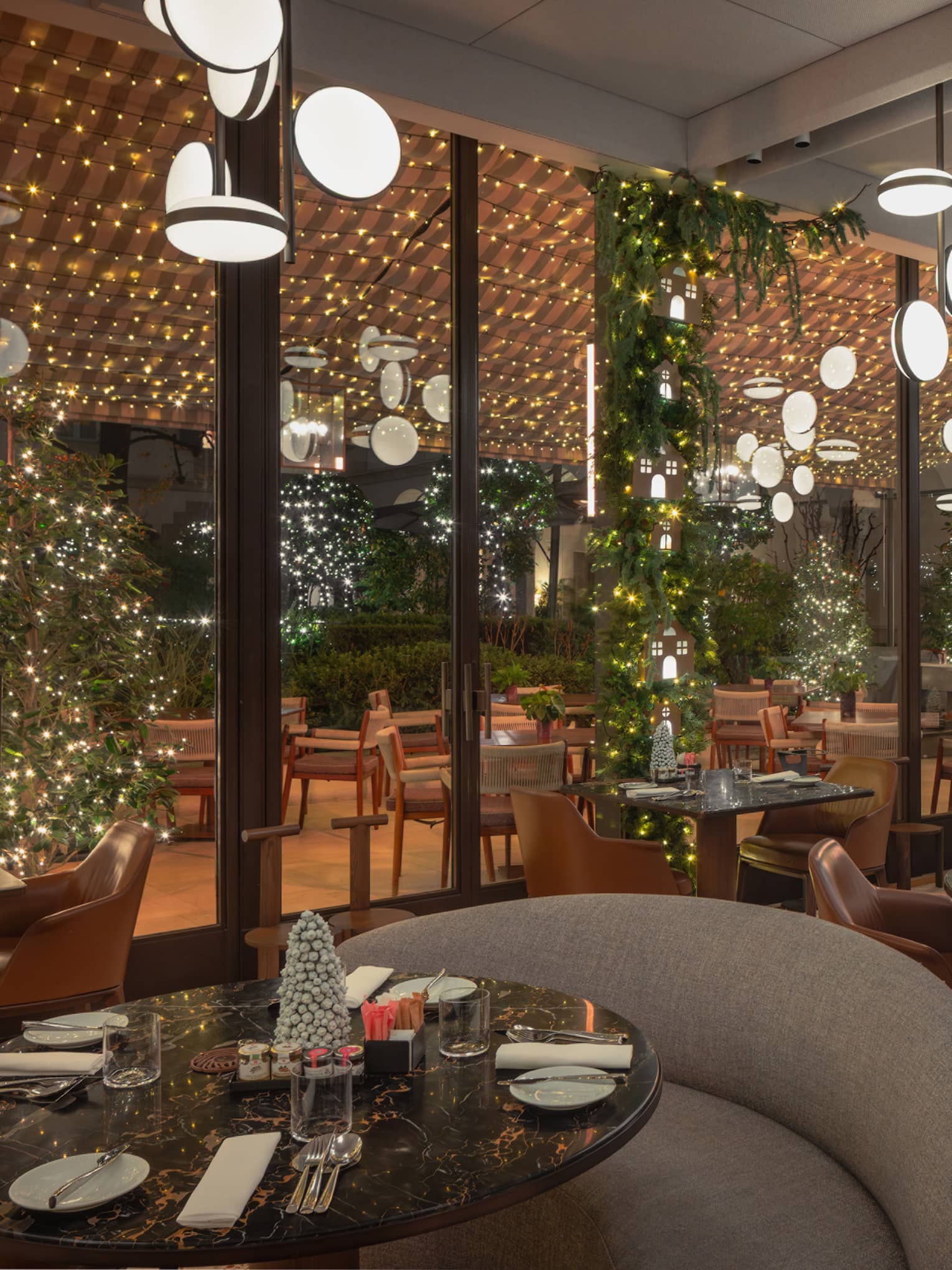 A chic interior dining space decorated with festive greenery and lights