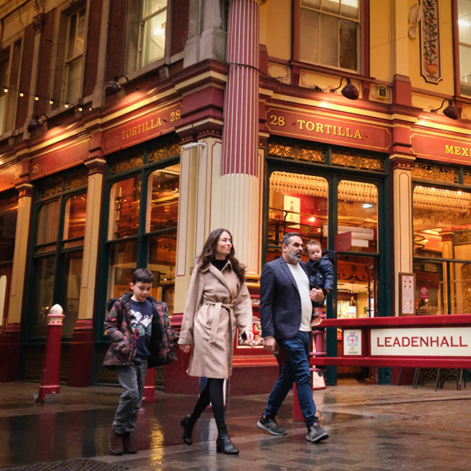A family walks through London city street at night