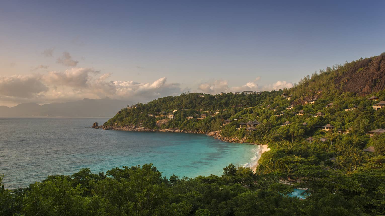 Aerial view of Petite Anse bay with blue ocean and buildings built into hillside