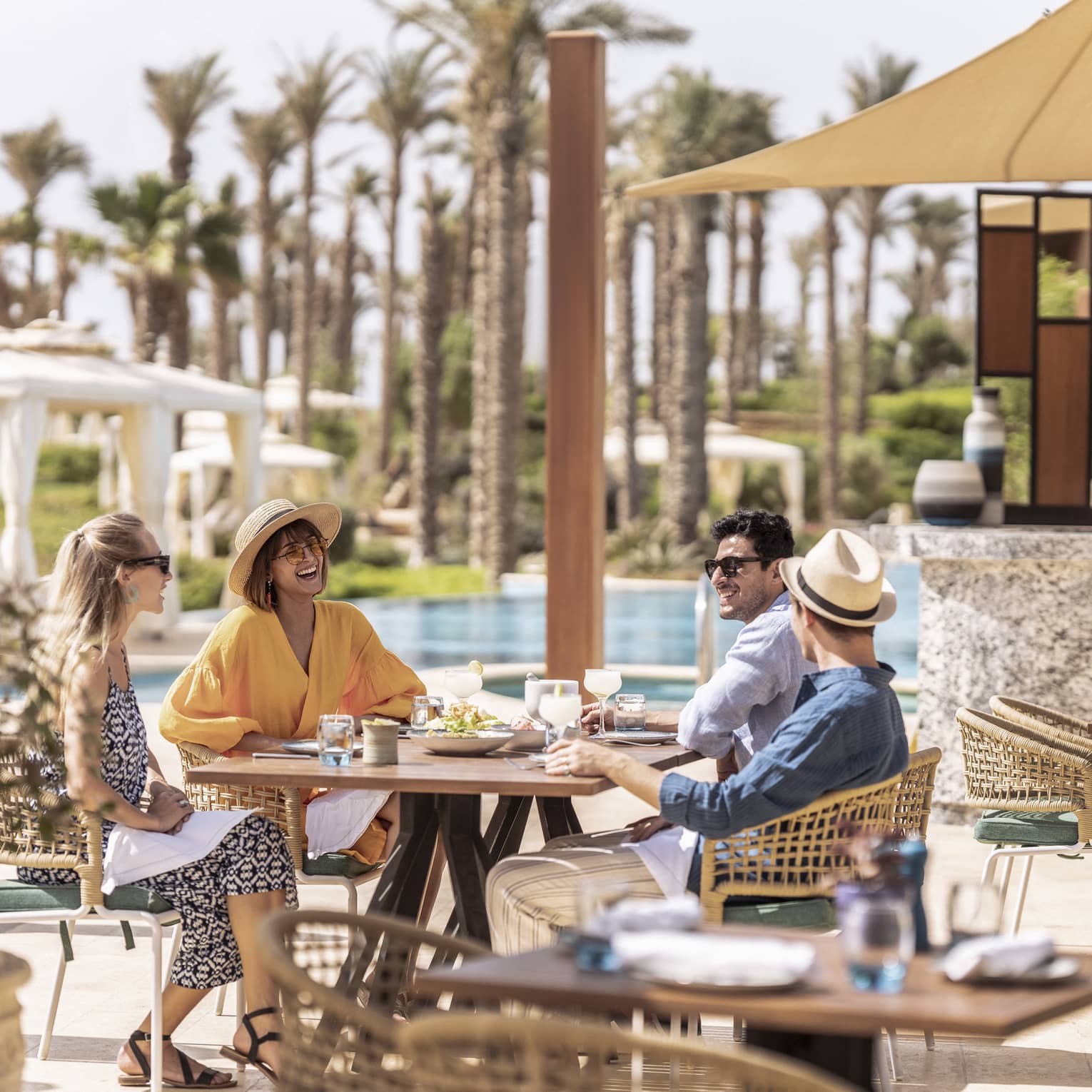 Friends enjoying lunch outdoors by the pool in luxury hotel