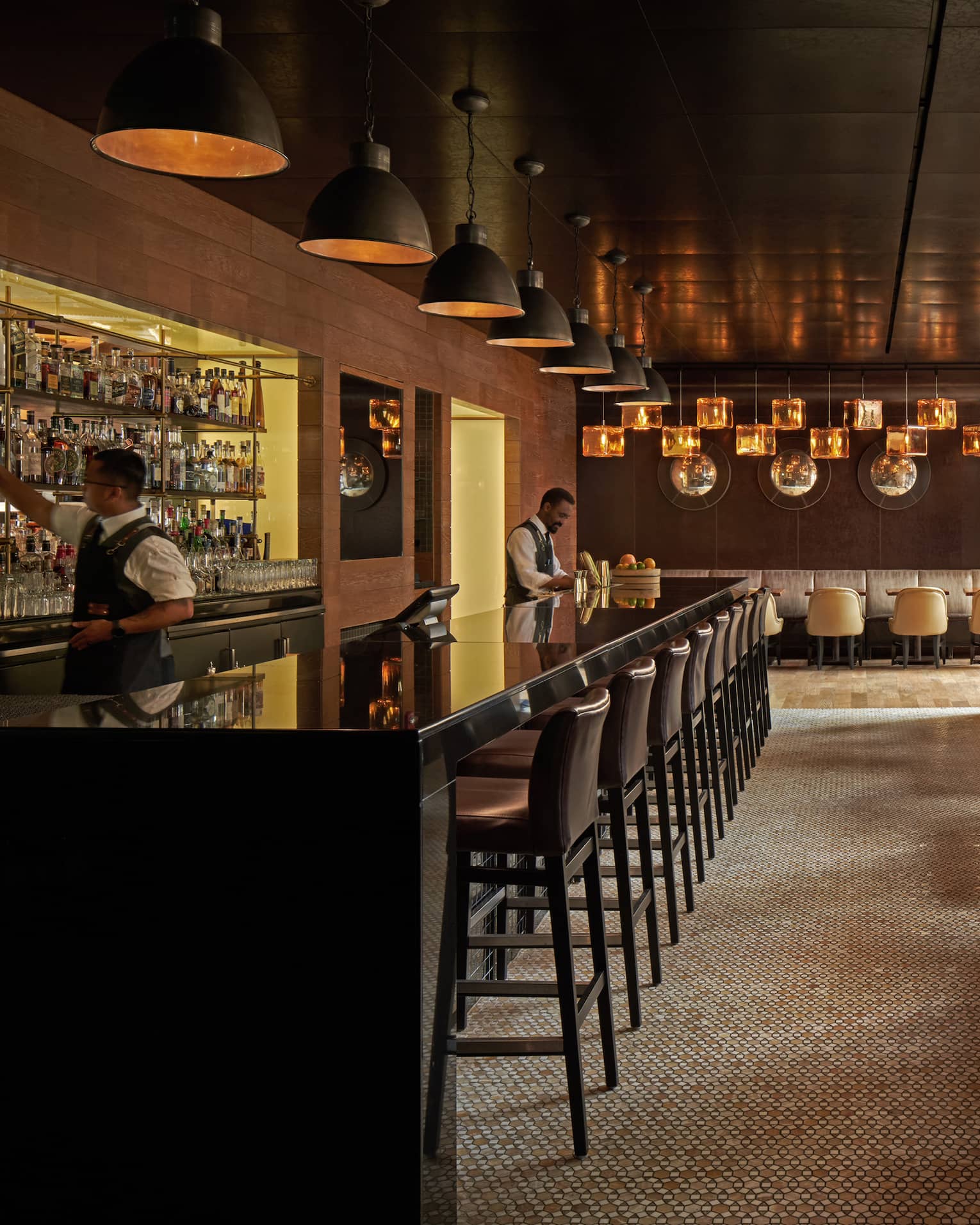 A dimly lit bar with dark wood stools and booths.