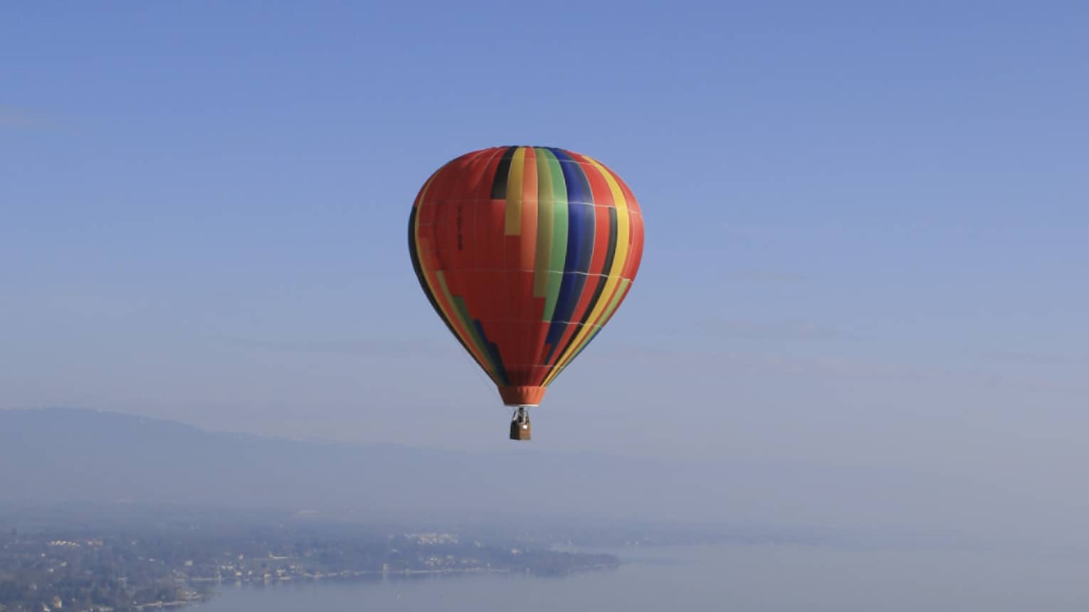 Colourful striped hot air balloon floating over Lake Geneva