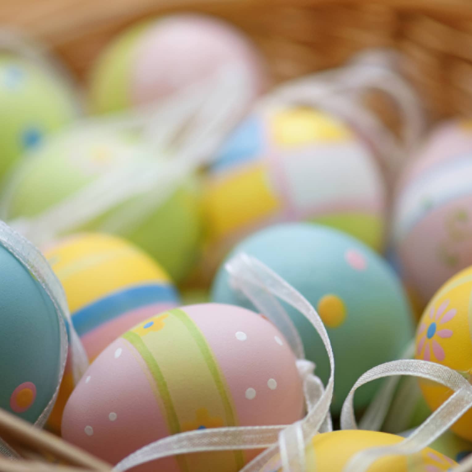 A basket of blue, pink, green and yellow colourful Easter eggs.