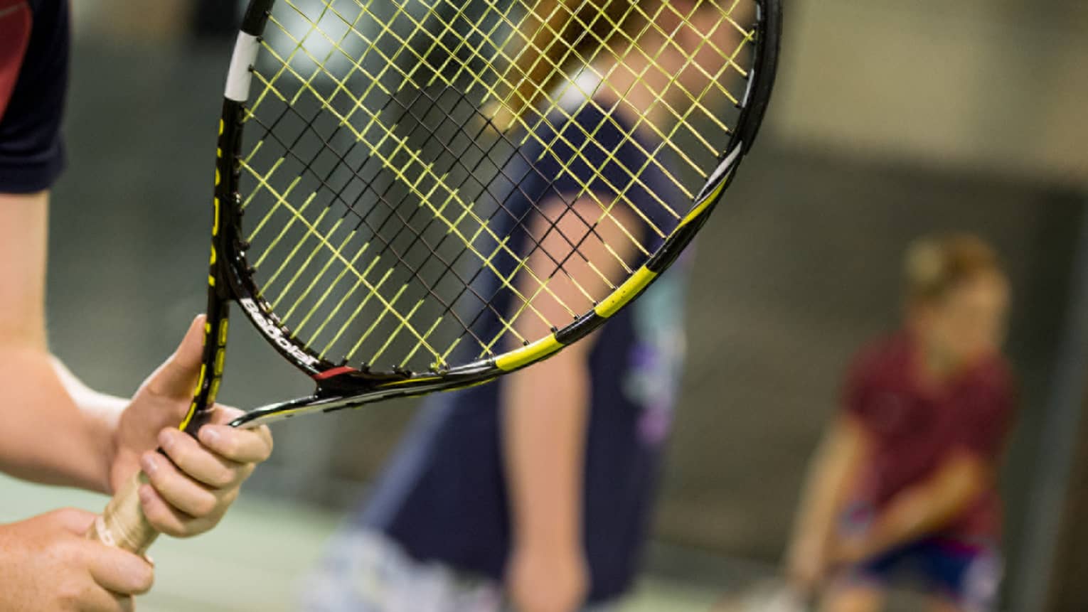 Close-up of hands holding yellow-and-black tennis racket