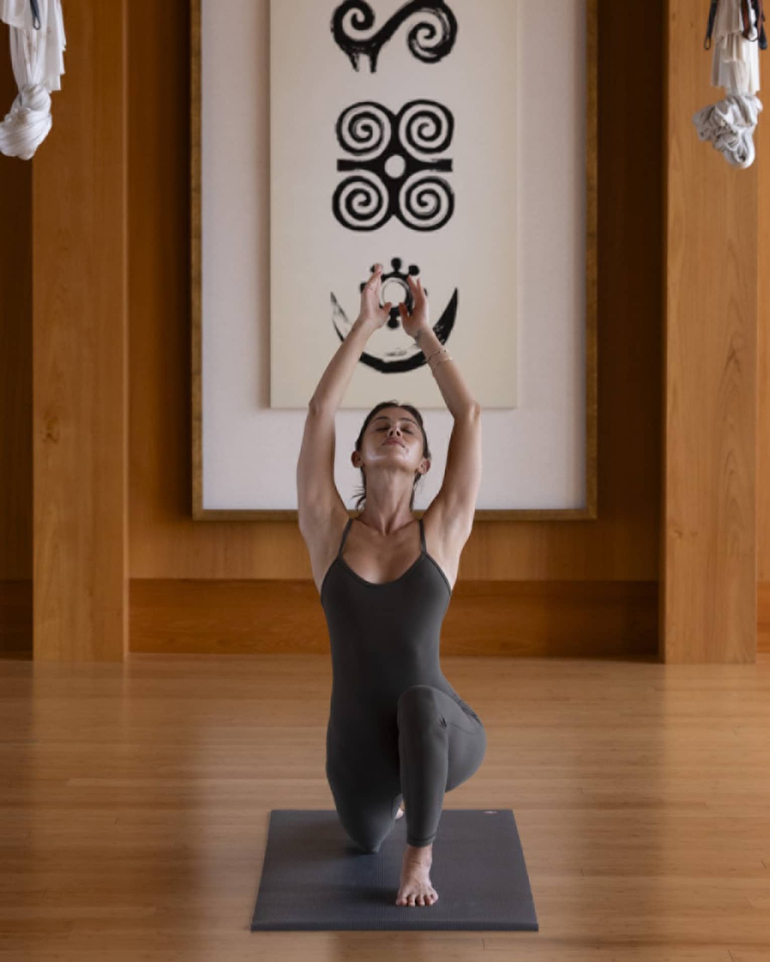 Woman practises yoga in indoor studio with wooden floors and walls