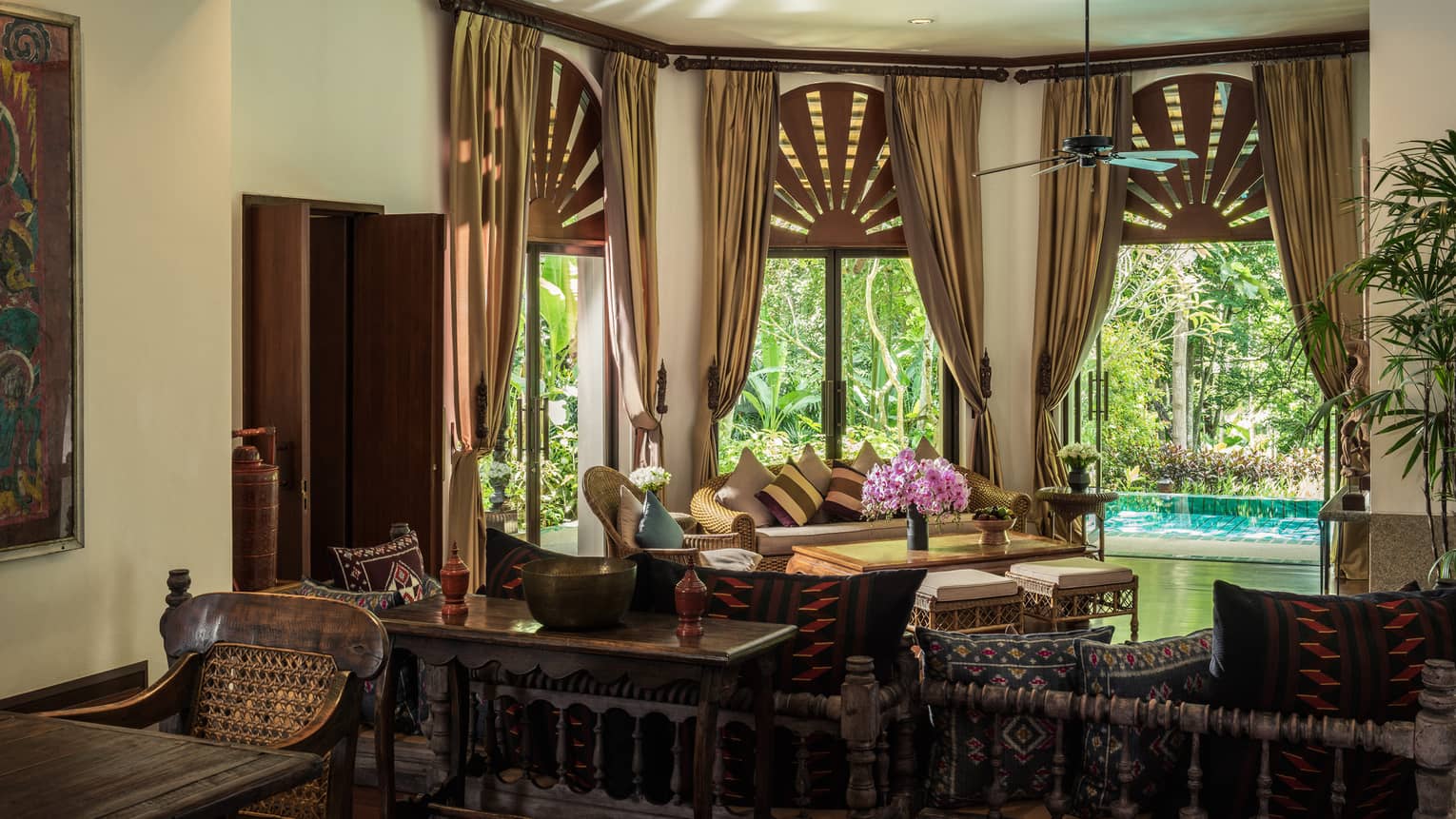 Tall bay windows with gold curtains over sofa, living room, plunge pool visible on patio
