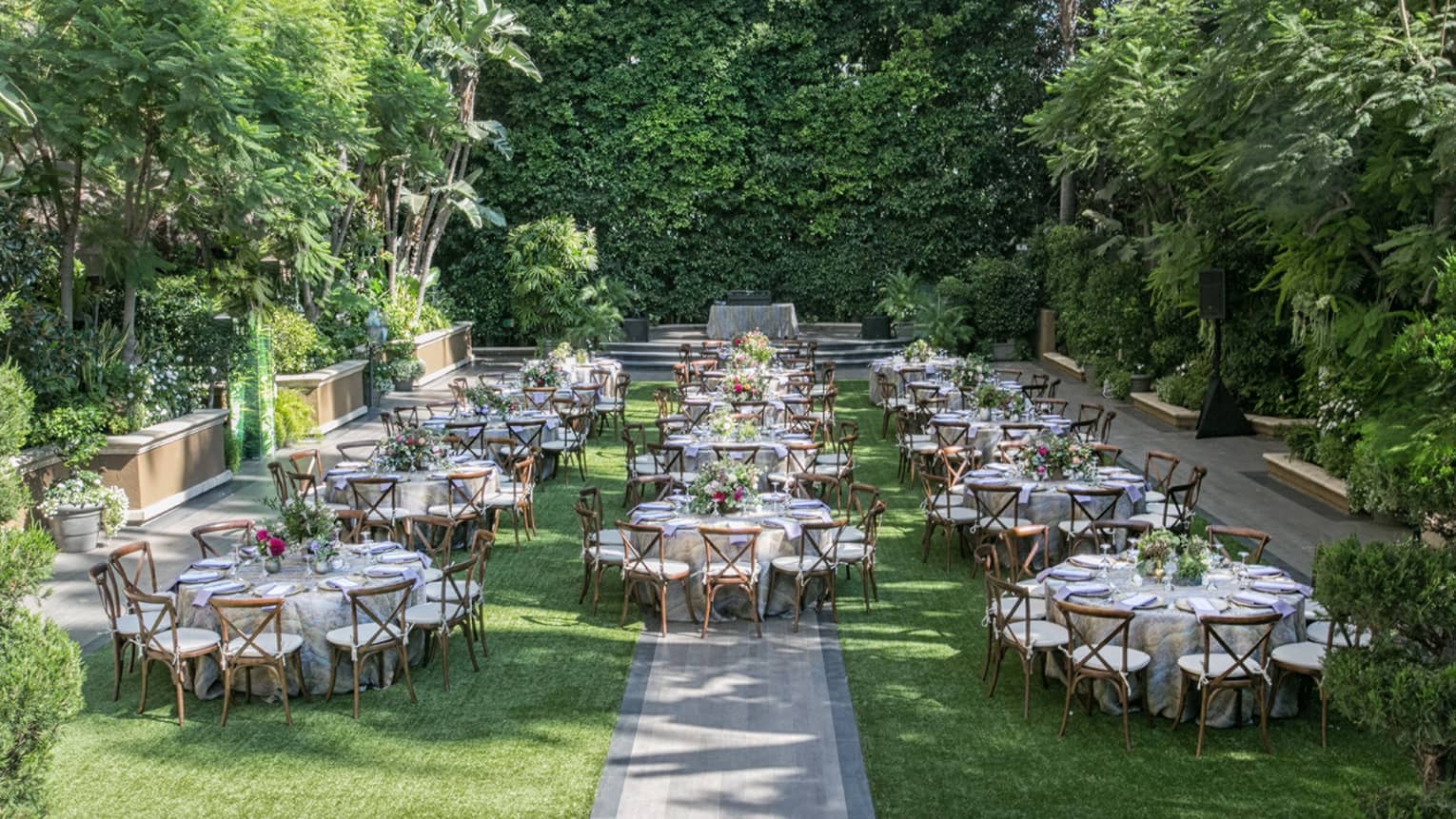View over sunny Wetherly Garden lawn with round banquet dining tables and chairs 