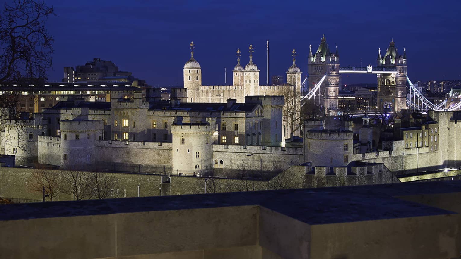 View over wall to Tower Bridge and the Tower of London at night