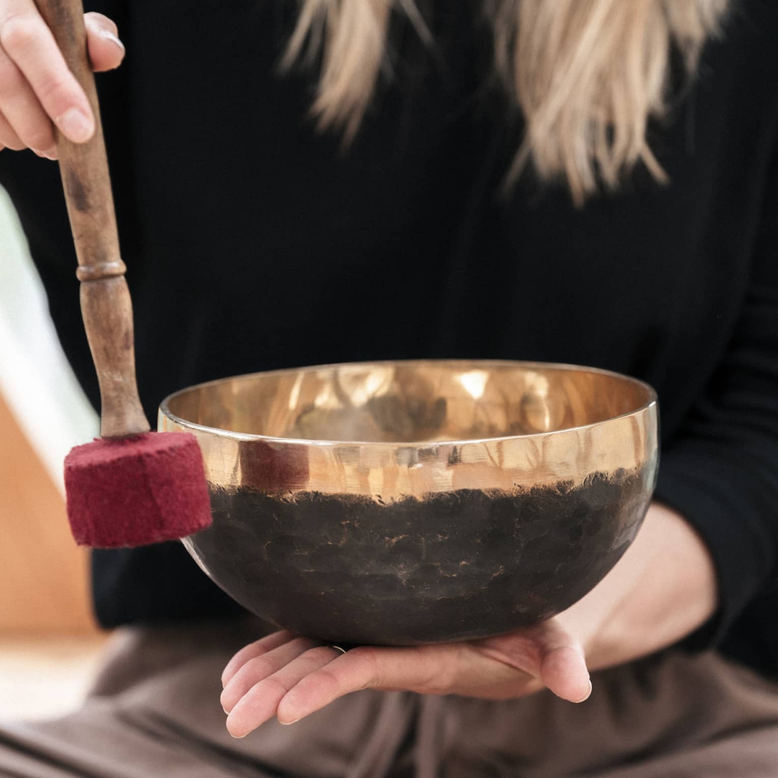 A person holding a Tibetan bowl and mallet