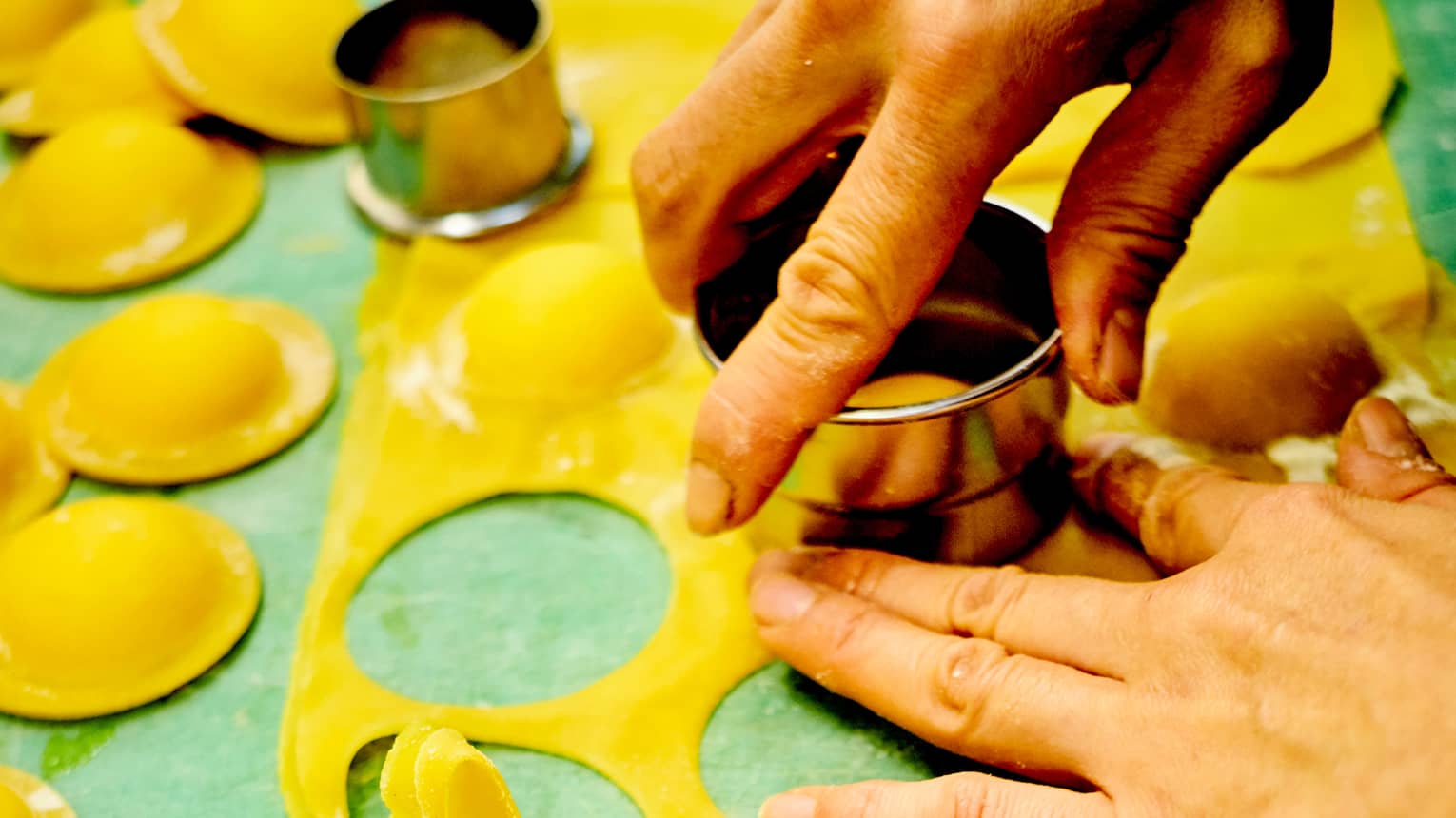 Close-up of chef hand-cutting pasta with round cookie cutters