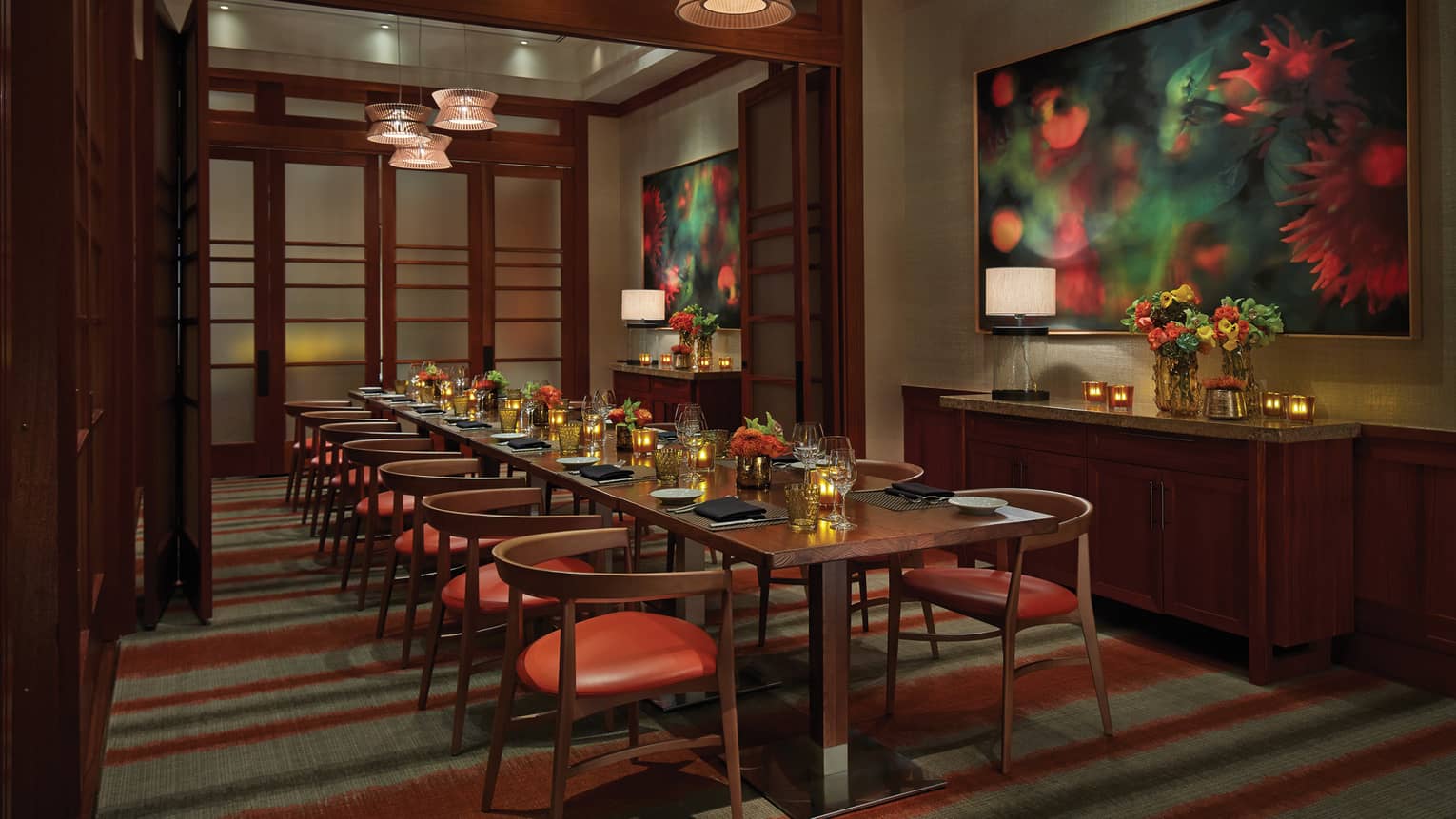 Private dining table with retro style red chairs in small room with dark wood accents