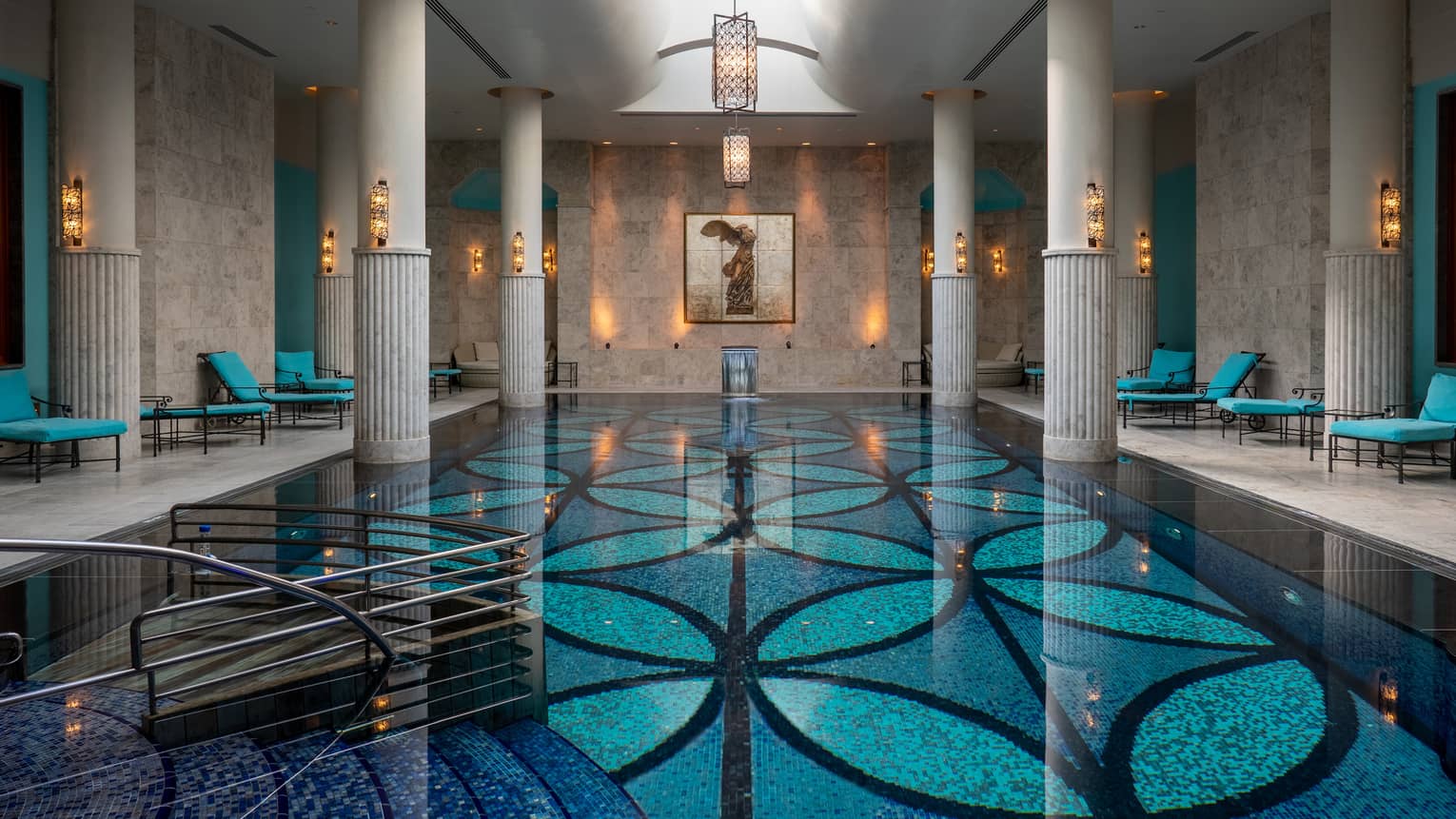 Indoor pool with blue-patterned floor, white up-lit columns and skylight