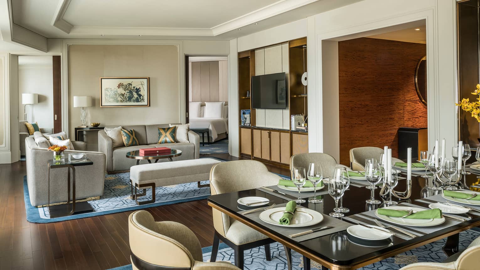 Royal Suite large dining table with formal place settings, green napkins by living room, TV console