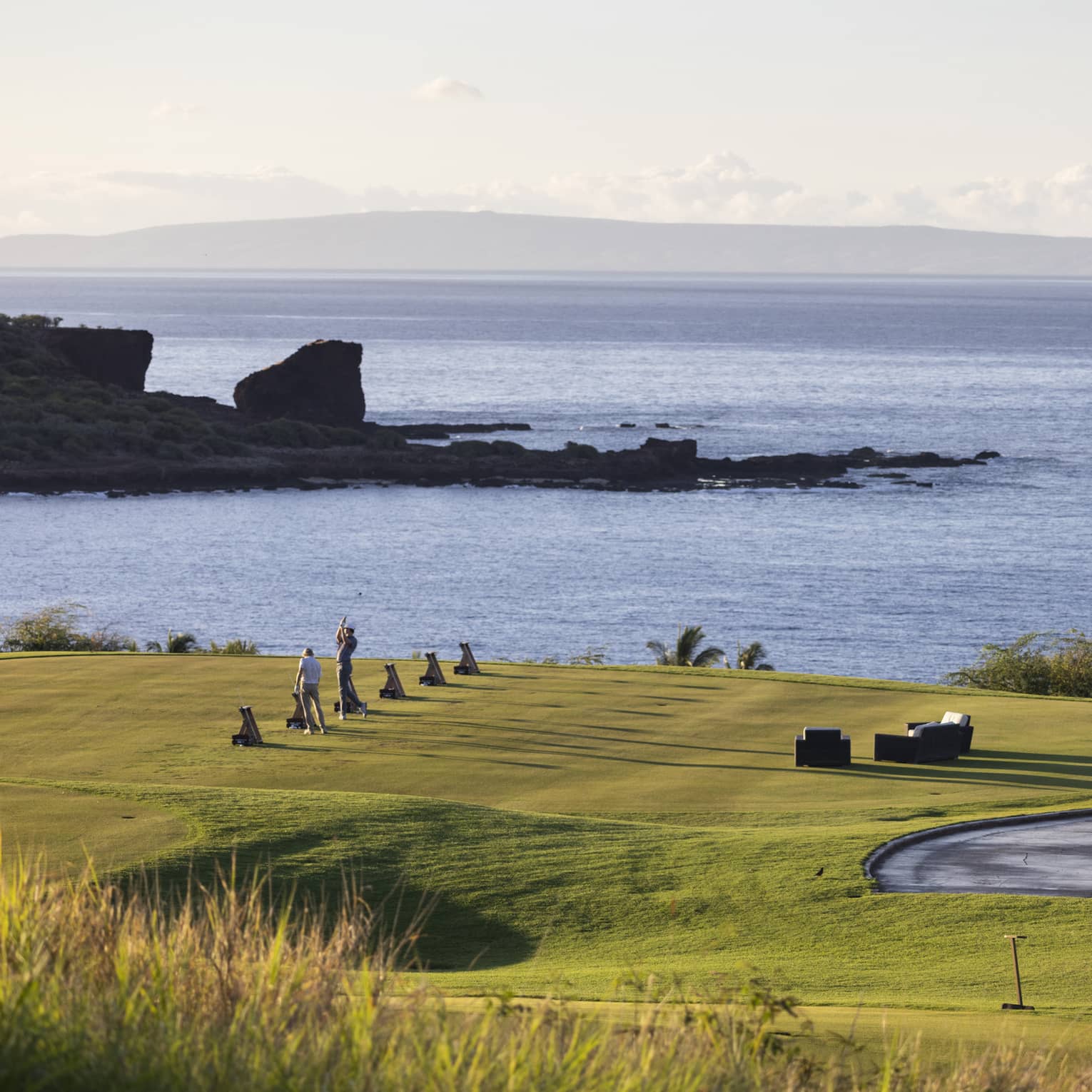 Golfers practicing on ocean-side golf course in Lanai, Hawaii