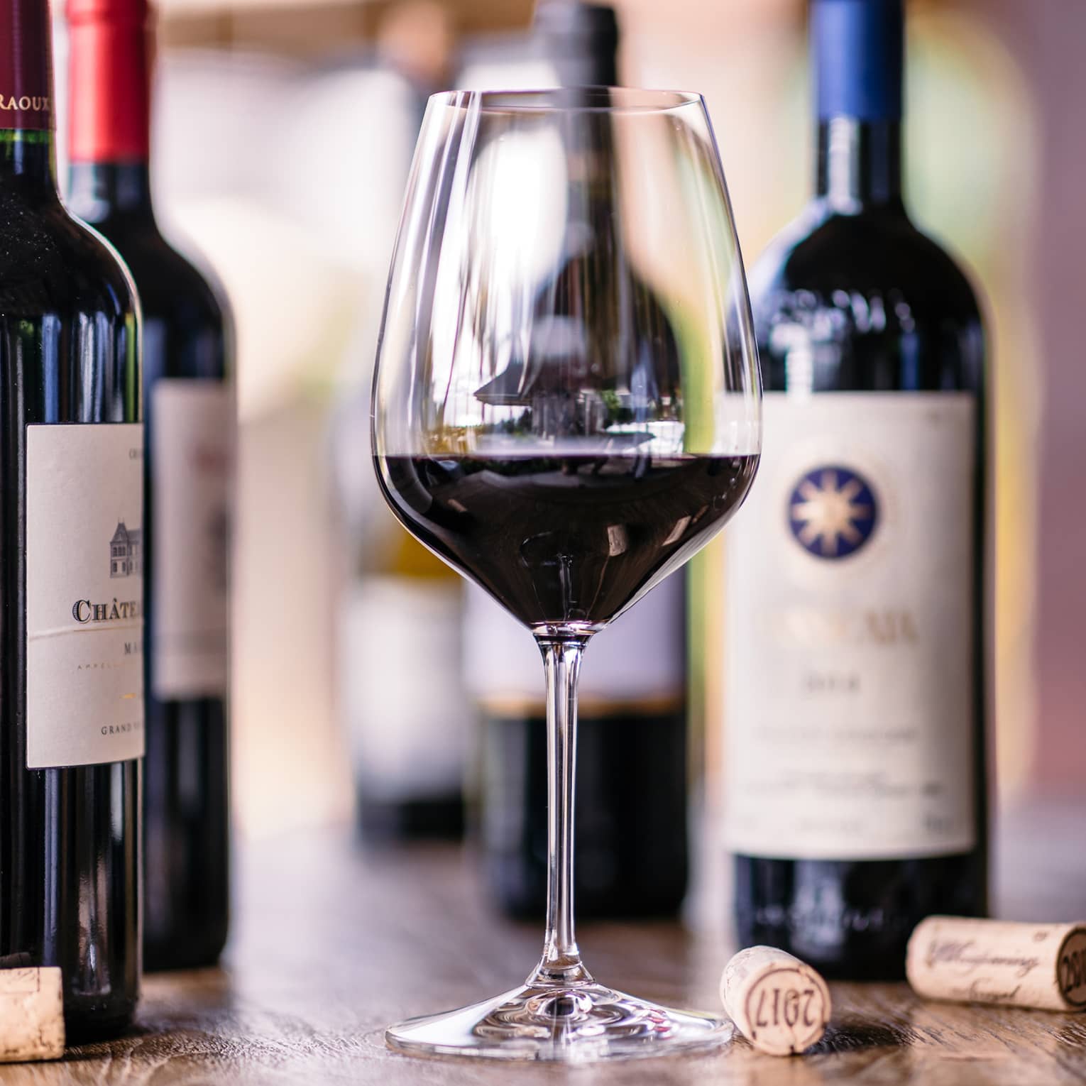 Closeup of glass of red wine, bottles beside it