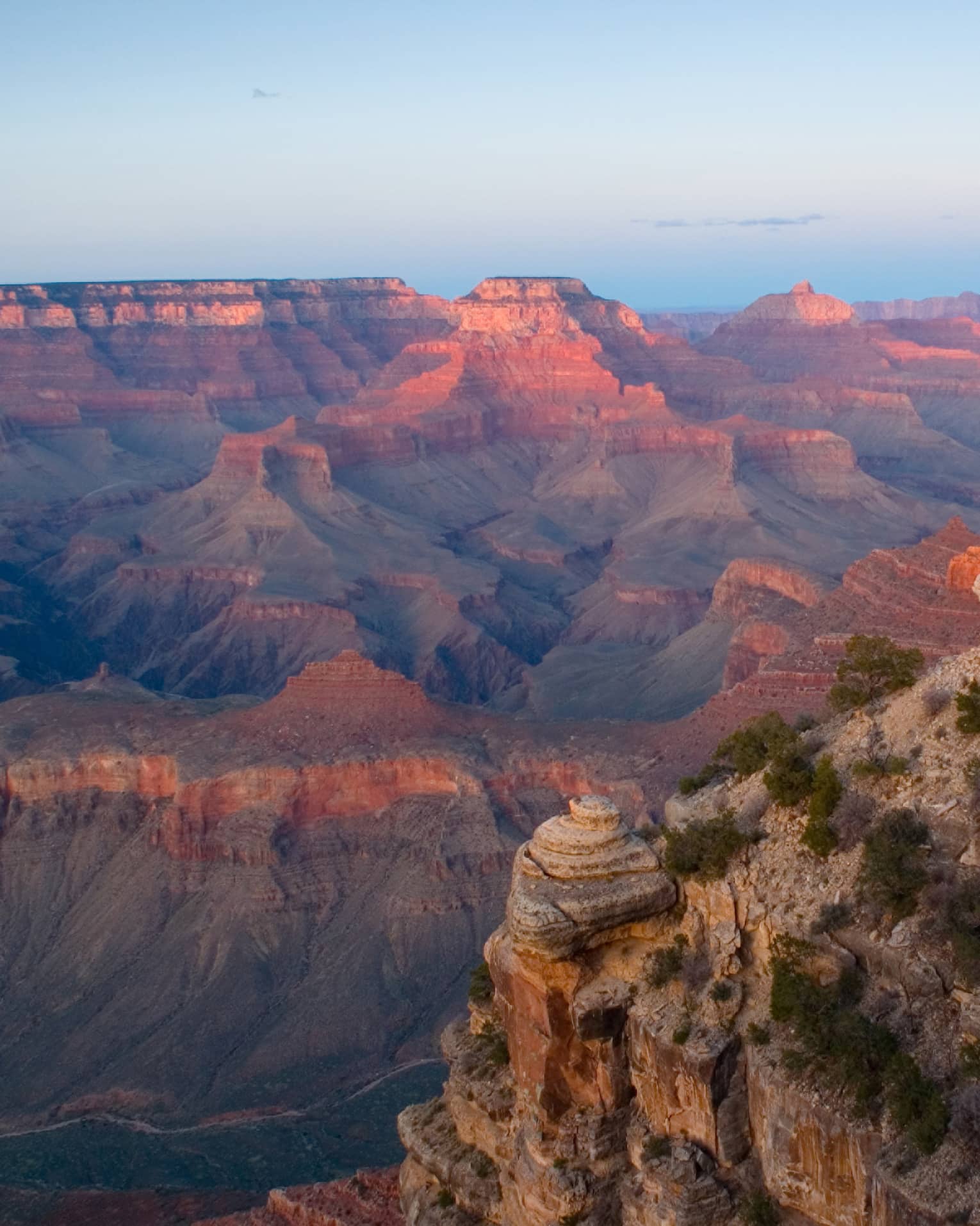 Sweeping view of Grand Canyon cliffs, canyon ridges, pink light from sunset