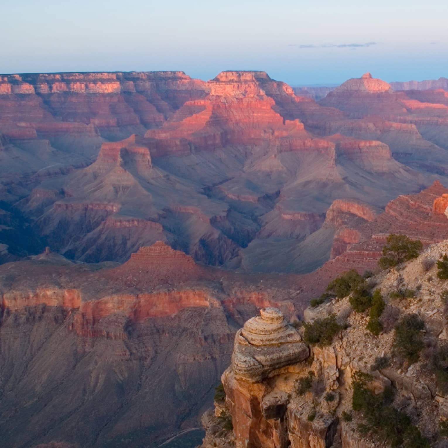 Sweeping view of Grand Canyon cliffs, canyon ridges, pink light from sunset