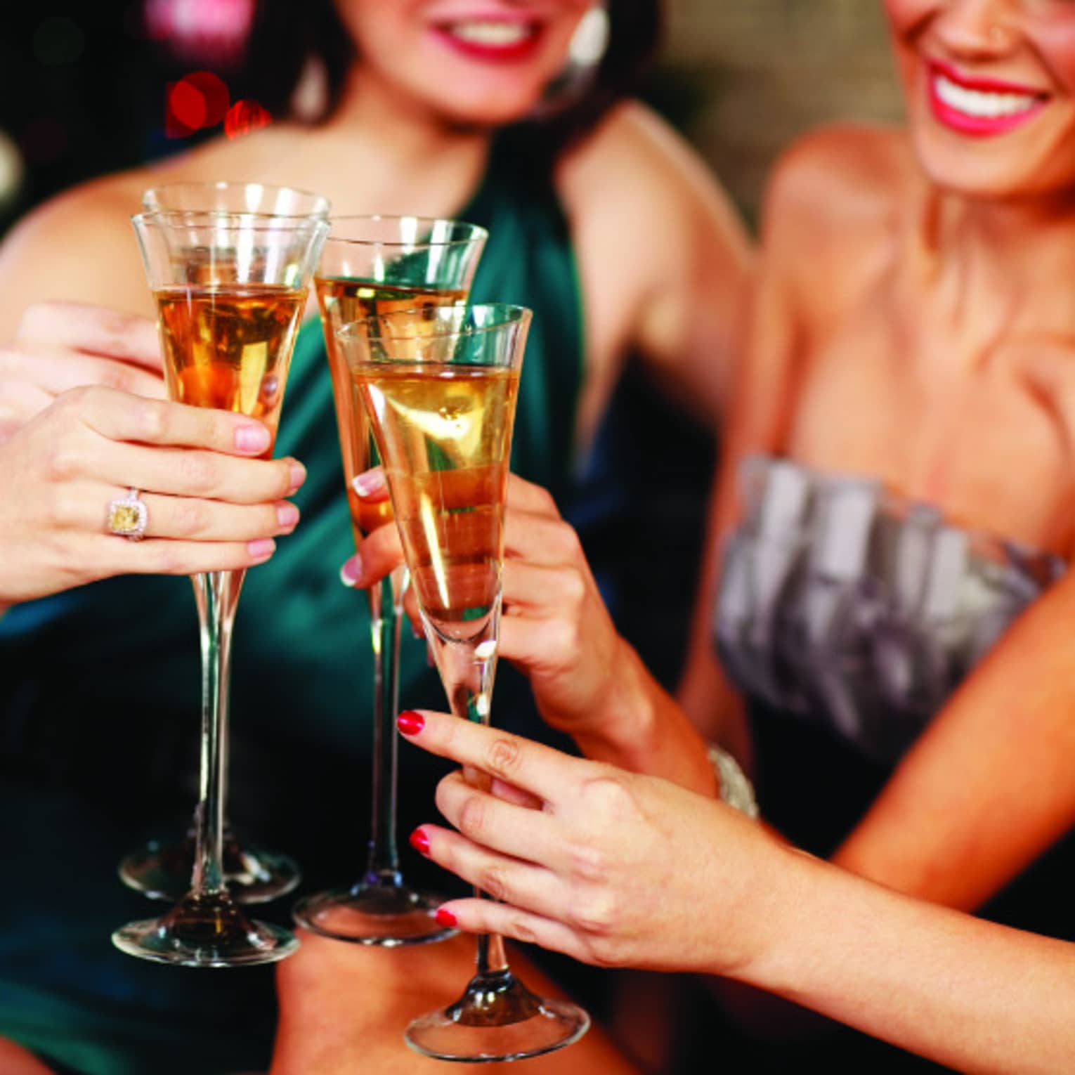 Close-up of women in evening gowns toasting with glasses of Champagne