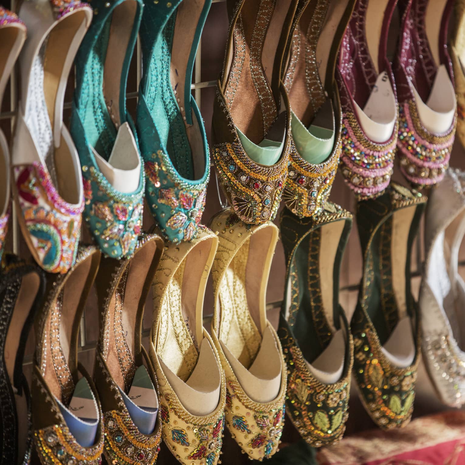 Rows of colourful shoes with beadwork and embroidery hang from market wall