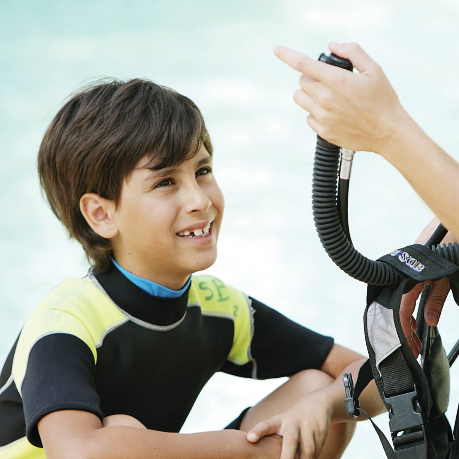 Boy in wetsuit in front of woman giving scuba diving instruction