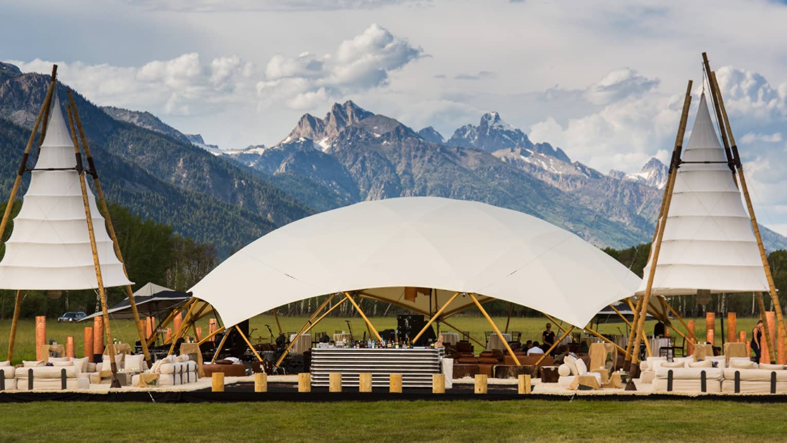 Cottonwood Lawn with three white canopies, white sofas and seating with views of Sleeping Indian Mountain 