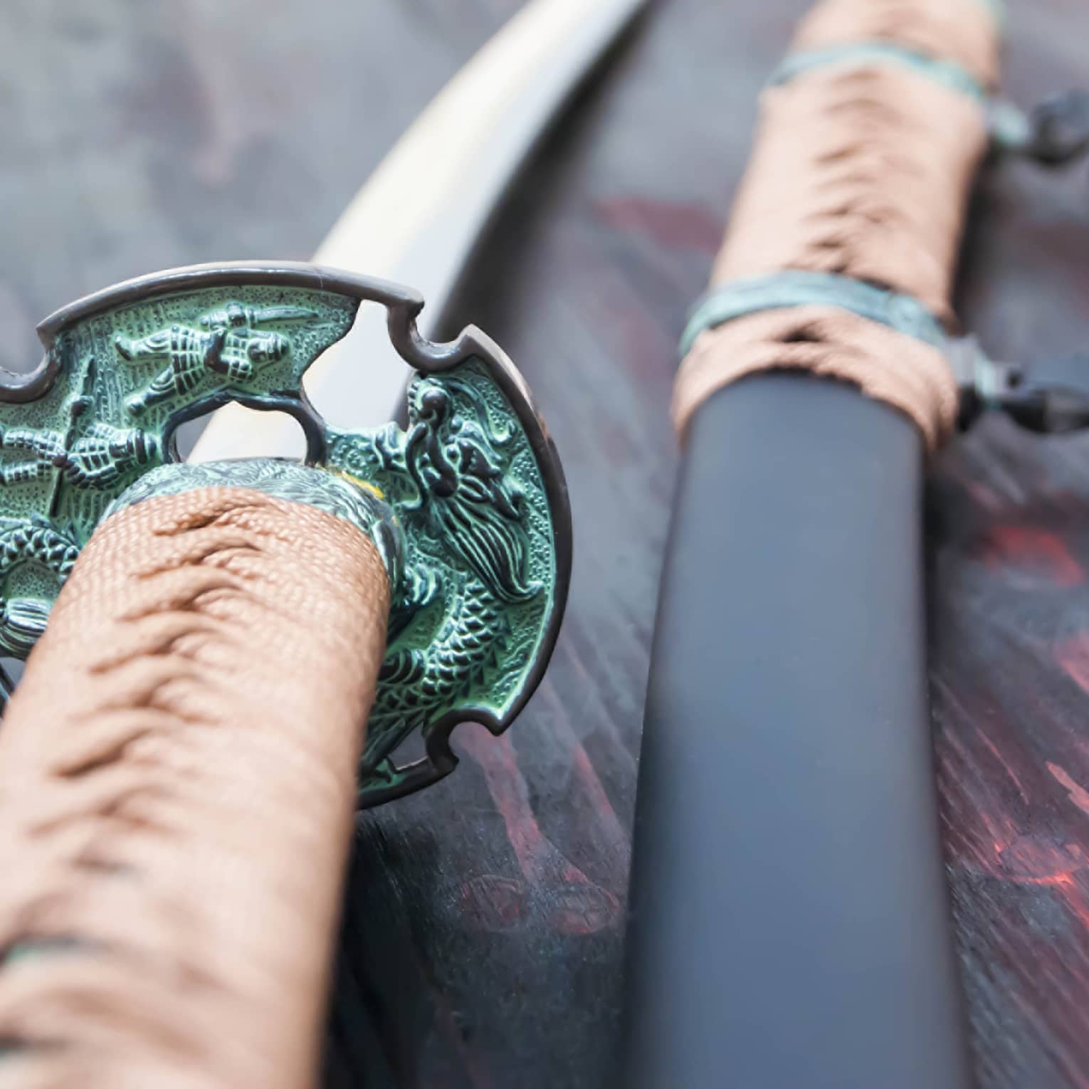 Two swords with green hilts lain on a red table.