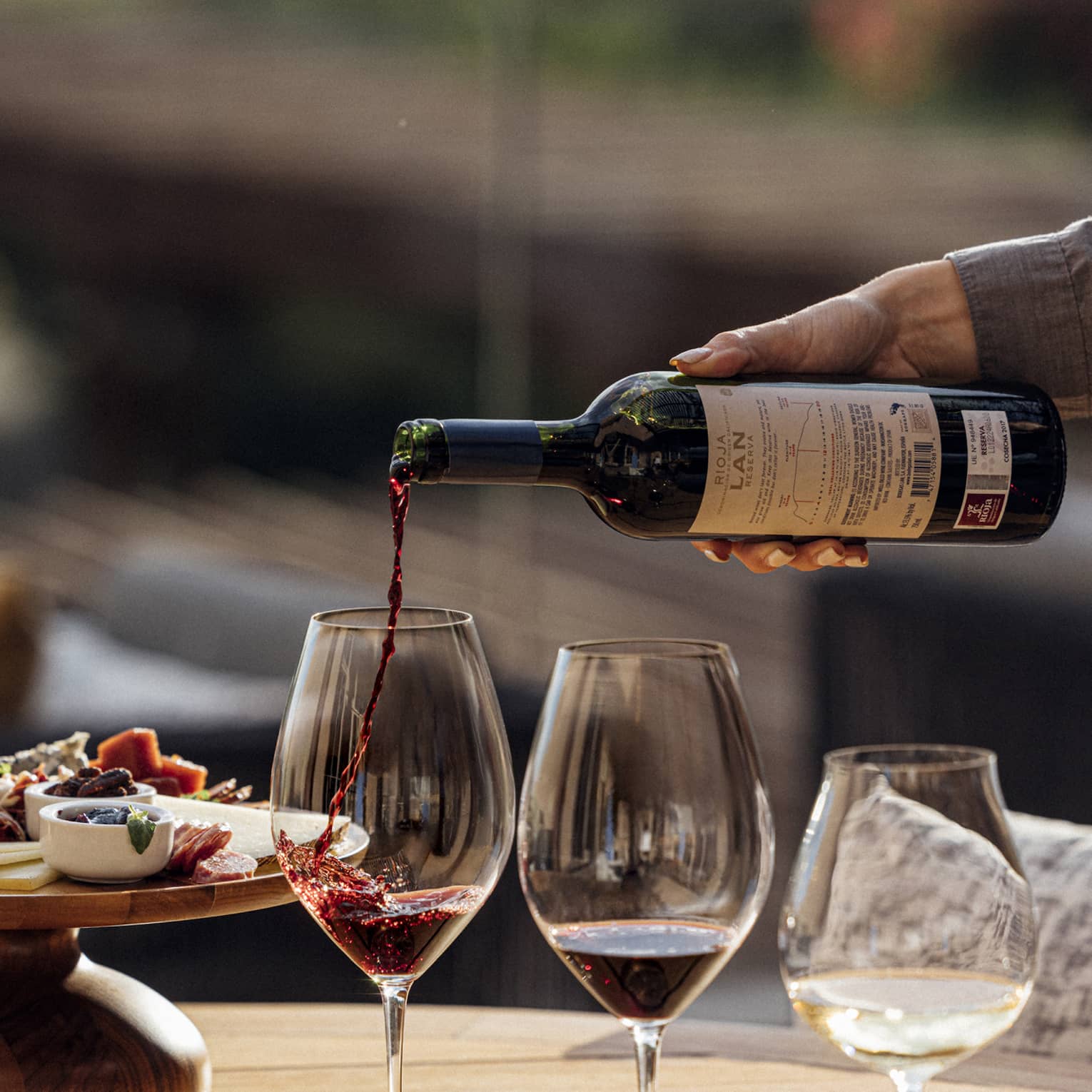 Three glasses of wine are poured next to a plate of charcuterie