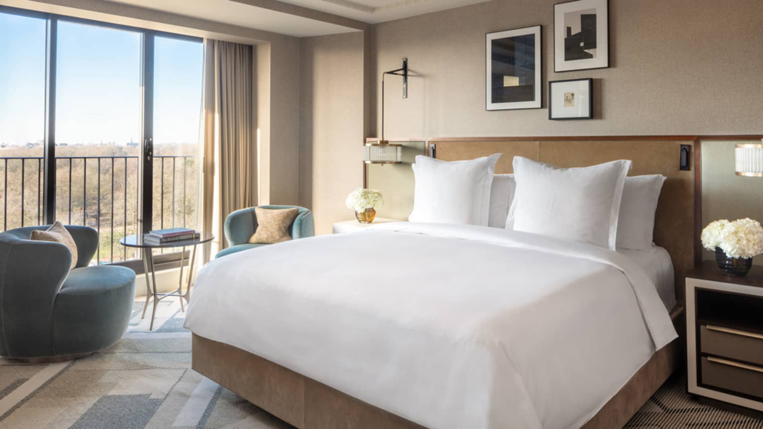 Premier King Room with white linens, blue accent chairs and table, floor-to-ceiling windows with city views 